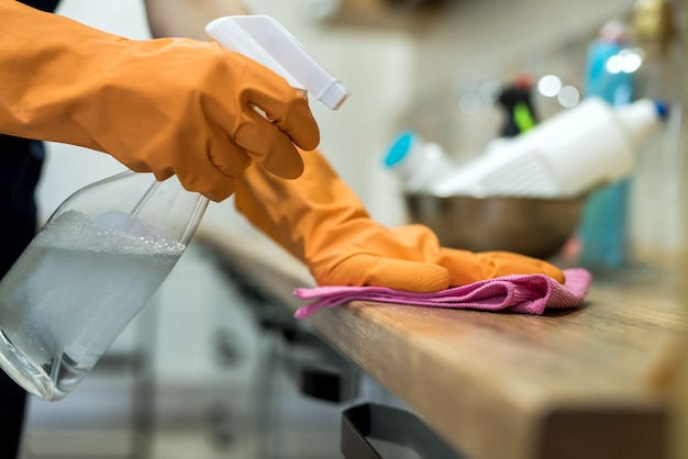 Mujer con guantes de goma y limpieza de la encimera de la cocina con una esponja. tareas del hogar