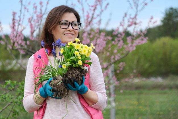 Mujer en guantes de jardín con flores para plantar