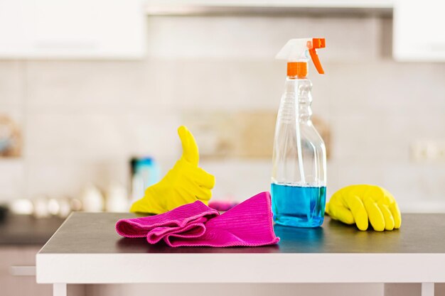 Foto mujer con guantes de protección limpiando el polvo con spray de limpieza y pulverizador concepto de servicio de limpeza