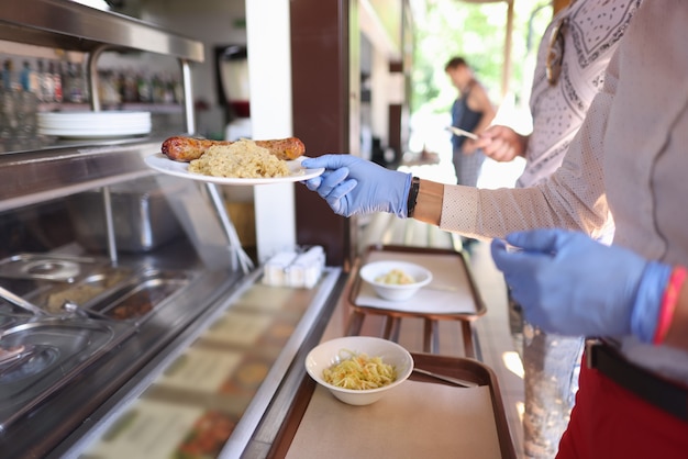 Foto mujer con guantes protectores en café toma plato de comida