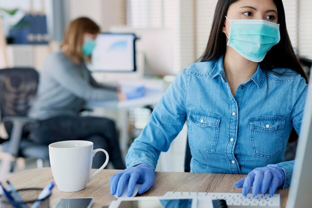 Foto mujer con guantes protectores y máscara en la oficina