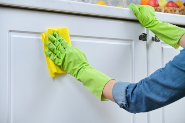 Mujer en guantes con un trapo limpiando la cocina