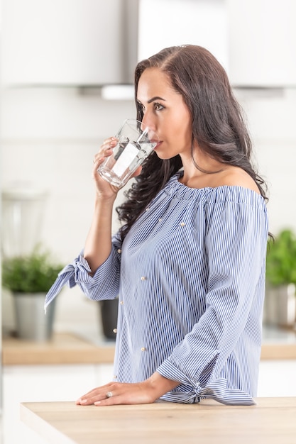 Foto mujer guapa bebe un vaso de agua pura dentro de la casa.