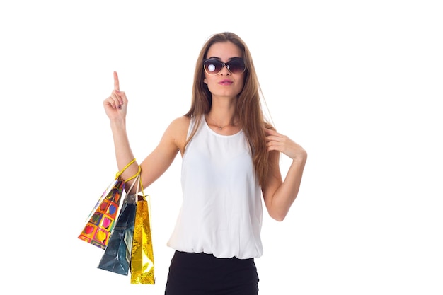 Mujer guapa joven en blusa blanca y falda negra con gafas de sol con bolsas de compras