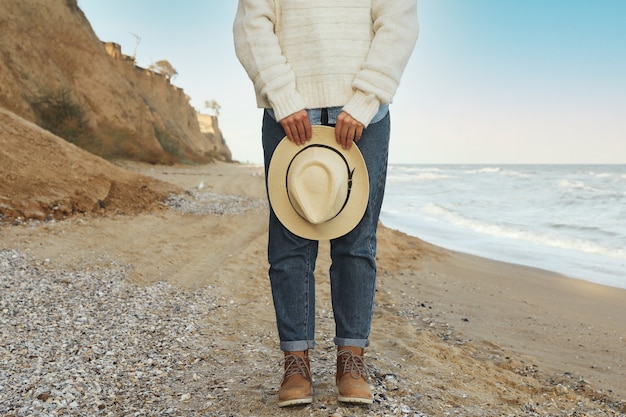 Mujer guapa mantenga sombrero en la playa de arena