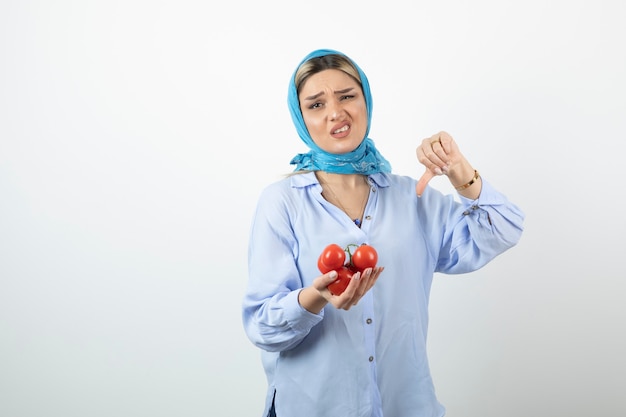 Mujer guapa en mantón azul mostrando el número cinco con la mano y sosteniendo tomates rojos