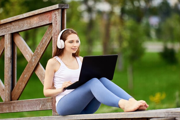 Mujer habla con amigos usando laptop e internet al aire libre