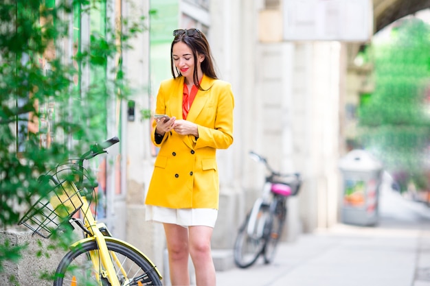 Mujer habla por su teléfono inteligente en la ciudad. Joven turista atractivo al aire libre en ciudad italiana