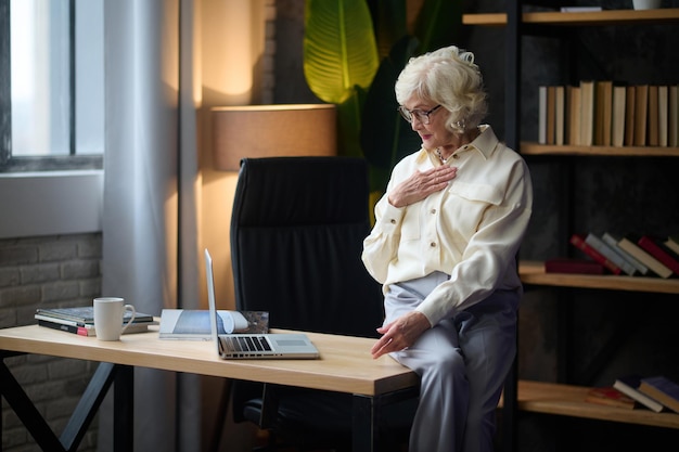 Mujer hablando con confianza mirando la computadora portátil sentada en el escritorio