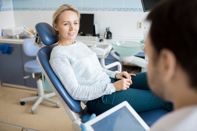 Mujer hablando con el dentista en el gabinete