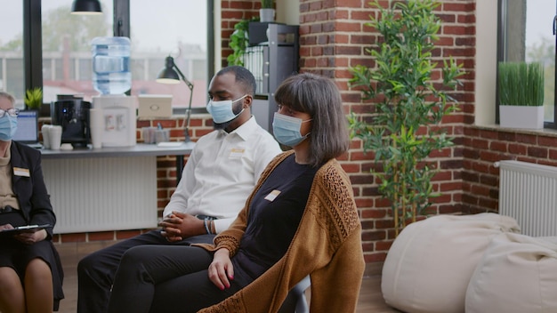 Mujer hablando de problemas de adicción al alcohol con un grupo de personas en una reunión durante la pandemia del coronavirus. Persona con mascarilla explicando problemas de salud mental en terapia.