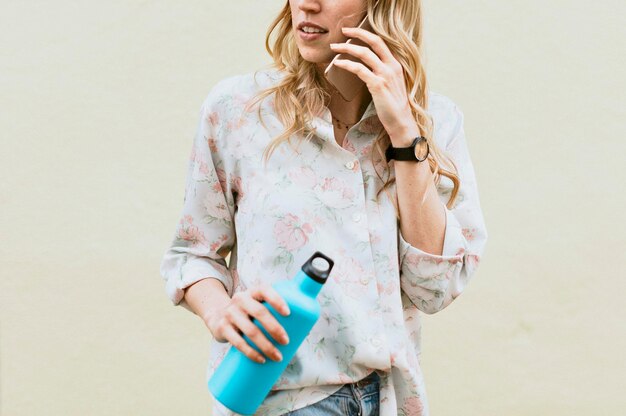 Mujer hablando por teléfono con una botella térmica