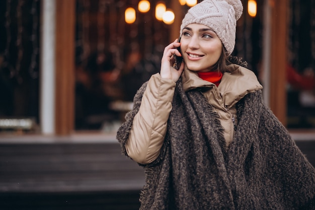 Mujer hablando por teléfono fuera de la barra en invierno