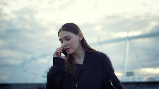 Mujer hablando por teléfono inteligente en la calle urbana chica seria a través de teléfono móvil