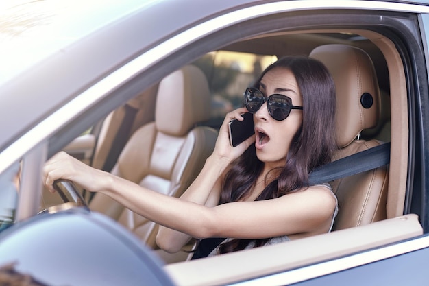 Mujer hablando por teléfono inteligente mientras conduce un automóvil