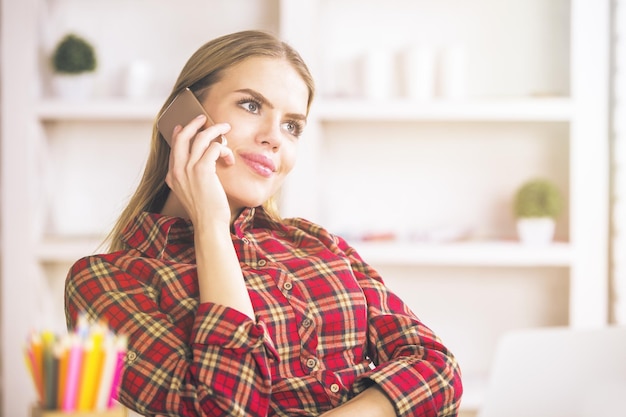 Mujer hablando por teléfono y lugar de trabajo