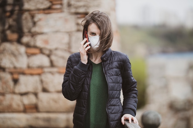 Una mujer hablando por teléfono con máscara de coronavirus