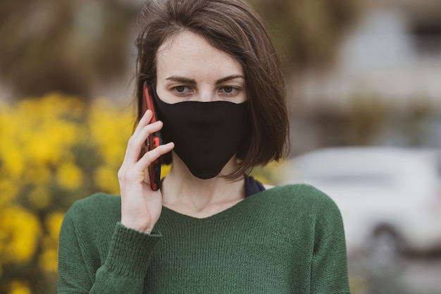 Una mujer hablando por teléfono con máscara de coronavirus
