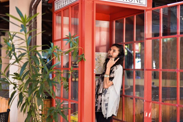 Foto mujer hablando por teléfono mientras está de pie en la cabina