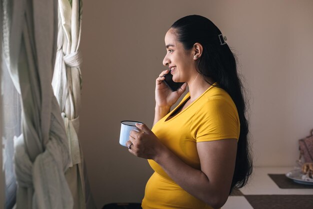 mujer hablando por teléfono mirnado por la ventana