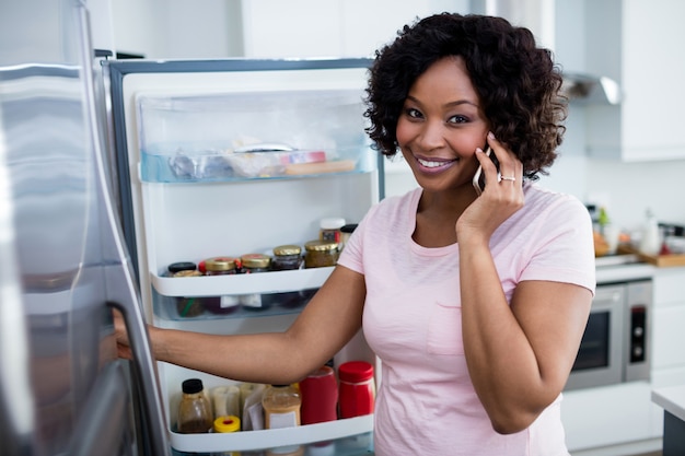 Mujer hablando por teléfono móvil en la cocina