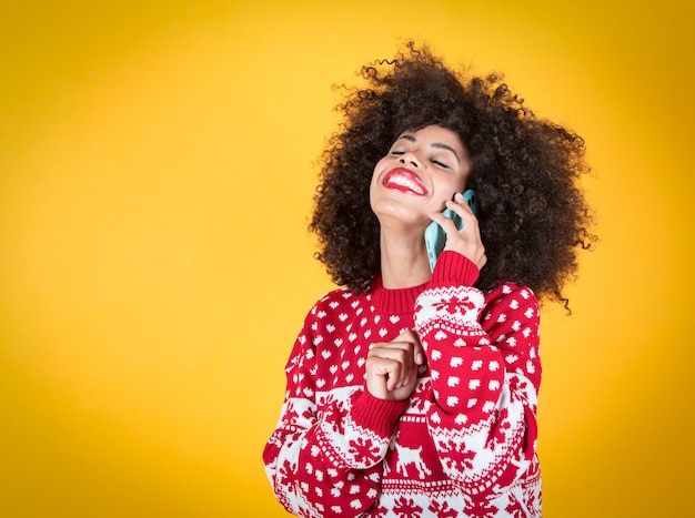 mujer hablando por teléfono móvil en navidad, fondo amarillo