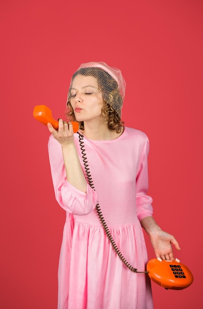 Mujer hablando por teléfono retro mujer encantadora en vestido rosa con auricular de teléfono mujer feliz sostiene