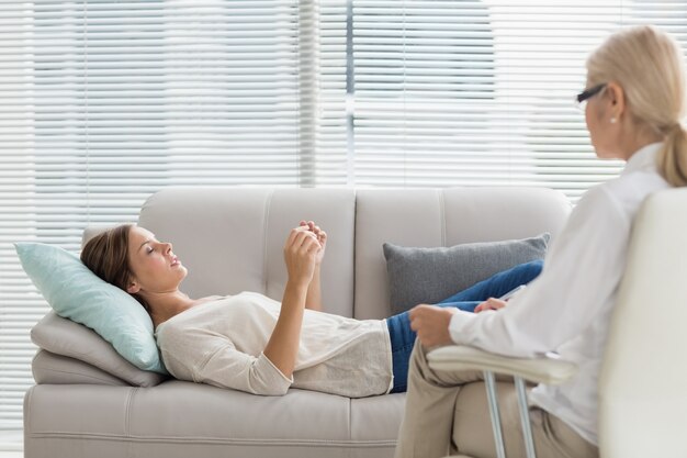 Mujer hablando con el terapeuta mientras está acostado en el sofá