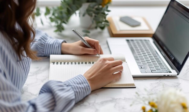 La mujer hace algunas notas en el cuaderno de la computadora portátil