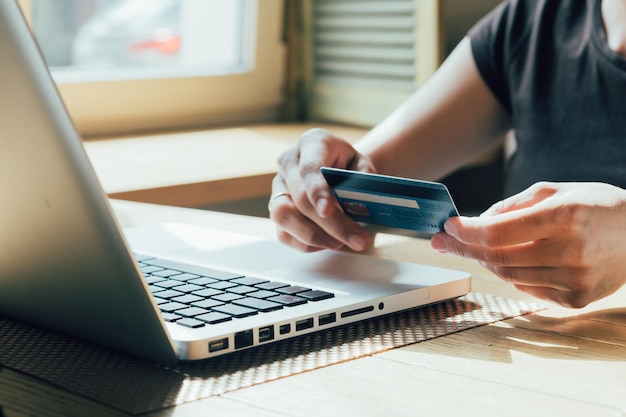 La mujer hace una compra en línea en una computadora usando una computadora portátil y una tarjeta de crédito