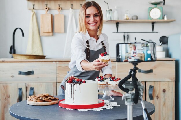 La mujer hace deliciosos dulces y pasteles. Proceso de grabación por teléfono inteligente en trípode.