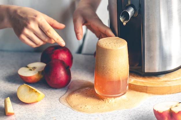 Una mujer hace jugo de manzana en casa con un exprimidor