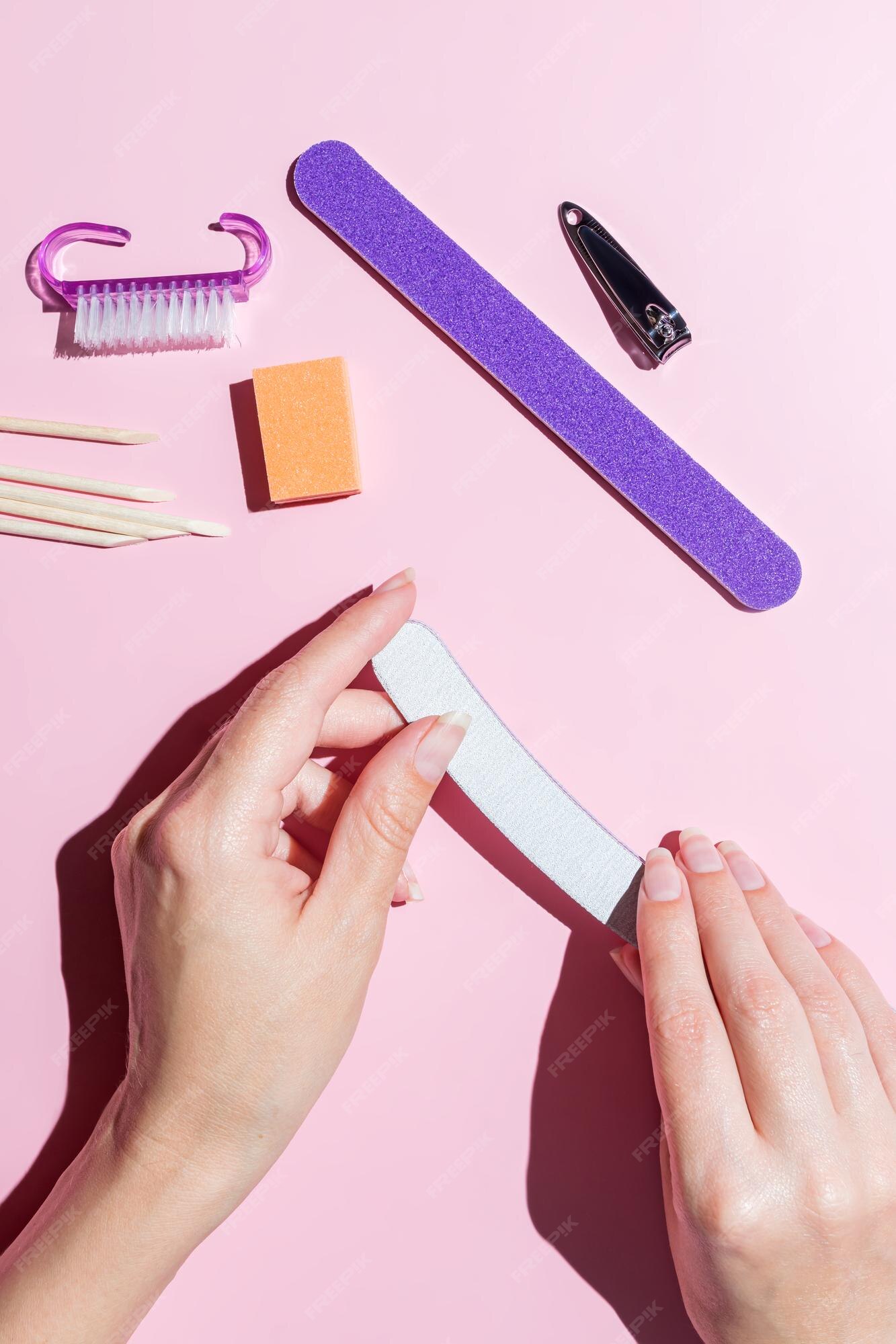 Una mujer se hace la manicura y se cuida las uñas y los dedos en la mesa en  casa. afilar las uñas alineadas con un primer plano de la vista superior del