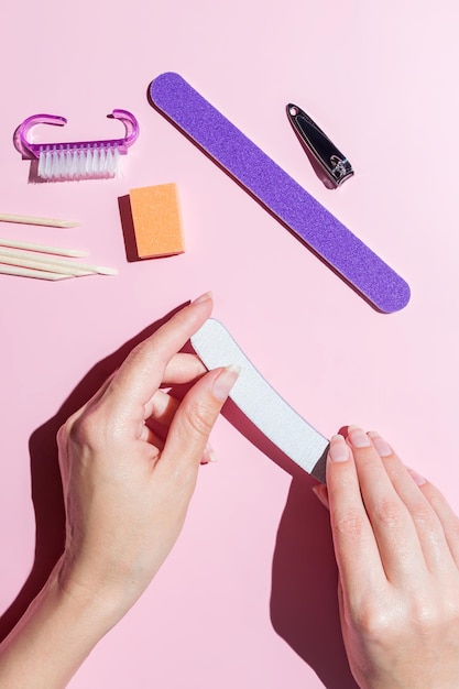 Una mujer se hace la manicura y se cuida las uñas y los dedos en la mesa en casa. Afilar las uñas alineadas con un primer plano de la vista superior del archivo.