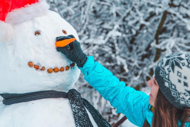 Mujer hace un muñeco de nieve en concepto de día de invierno helado