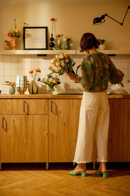 La mujer hace un ramo de flores en la cocina