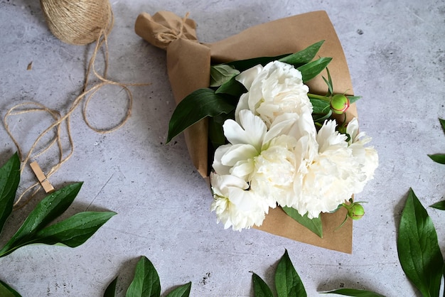 Una mujer hace un ramo de peonías un ramo de flores de poda de papel kraft stylite hace un ramo