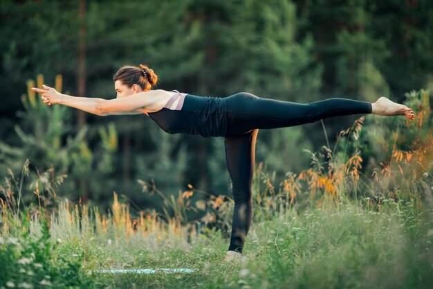 Una mujer hace yoga al aire libre El concepto de deporte