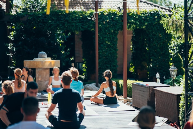 Foto una mujer hace yoga junto con su grupo al aire libre.