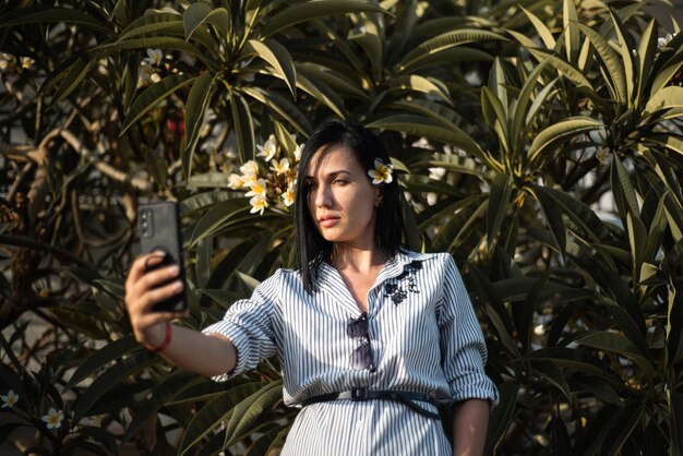 Mujer hacer selfie en jardín con flores