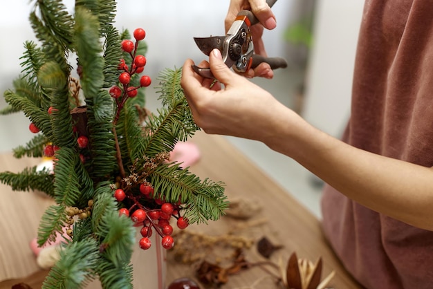 Foto mujer haciendo arreglos navideños con ramas de abeto artesanía decoración hecha a mano