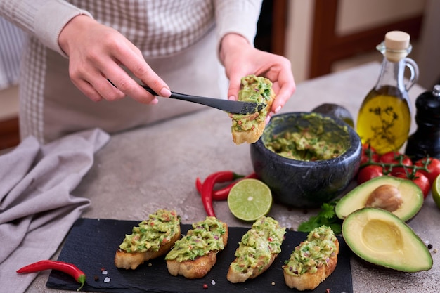 Foto mujer haciendo bruschetta con guacamole recién hecho en cocina doméstica