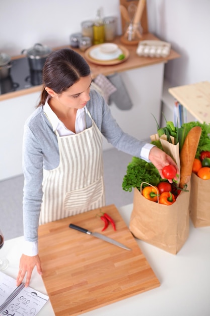 Mujer haciendo comida saludable de pie sonriendo en la cocina