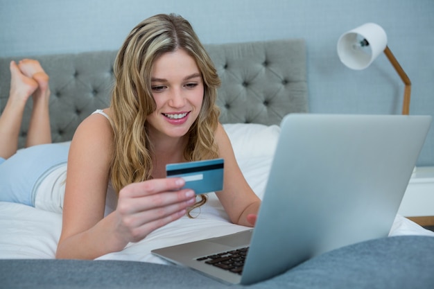 Foto mujer haciendo compras en línea con su computadora portátil en la cama