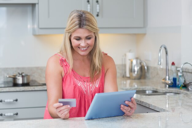 Mujer haciendo compras en línea en tableta digital en la cocina