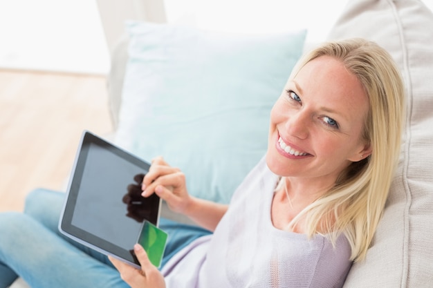 Mujer haciendo compras en línea en tableta digital en la sala de estar