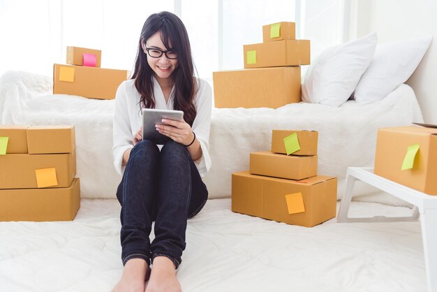 Mujer haciendo compras en línea a través de una tableta digital mientras está sentada en la cama en casa