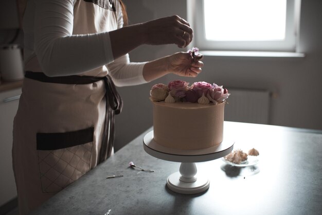 Mujer haciendo decoración de tartas con flores rosas