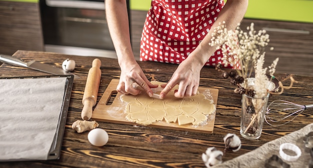 Mujer haciendo deliciosas galletas caseras en forma de corazón en su cocina