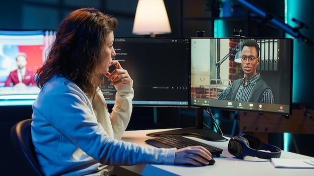 Mujer haciendo depuración de software ayudada por un compañero de trabajo en videocall